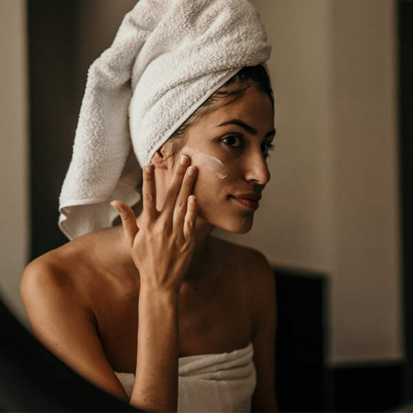 woman applying moisturizer on face